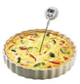 Photograph of a quiche with a thermometer in it.