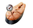 Photograph of a salmon steak with a thermometer in it.