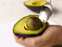 Photograph of spooning out the avocado pit.